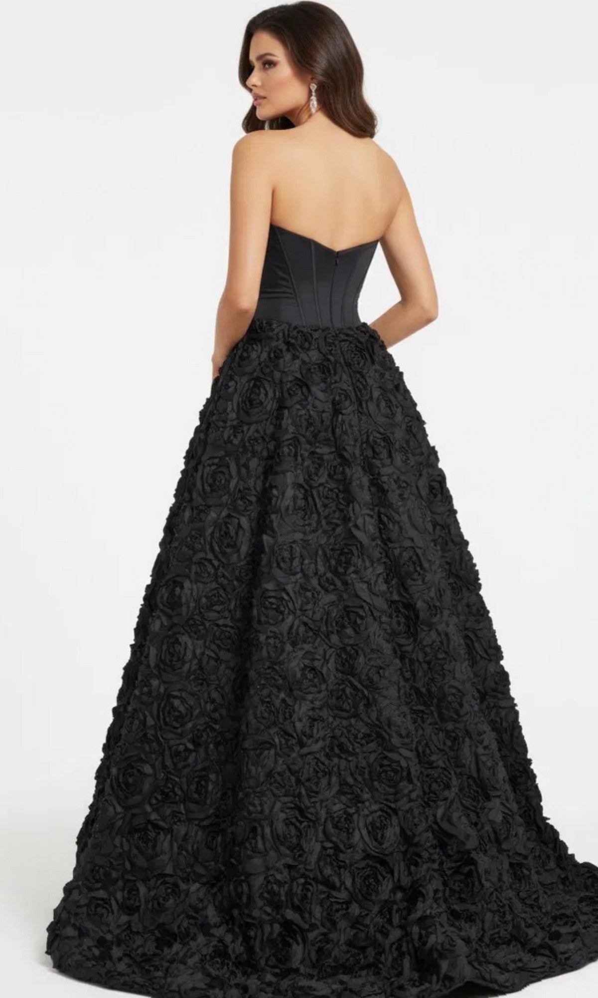 A woman models the Jovani 47695 Long Prom Dress, featuring a strapless corset bodice and a voluminous 3D rosette skirt, posed against a plain light background.